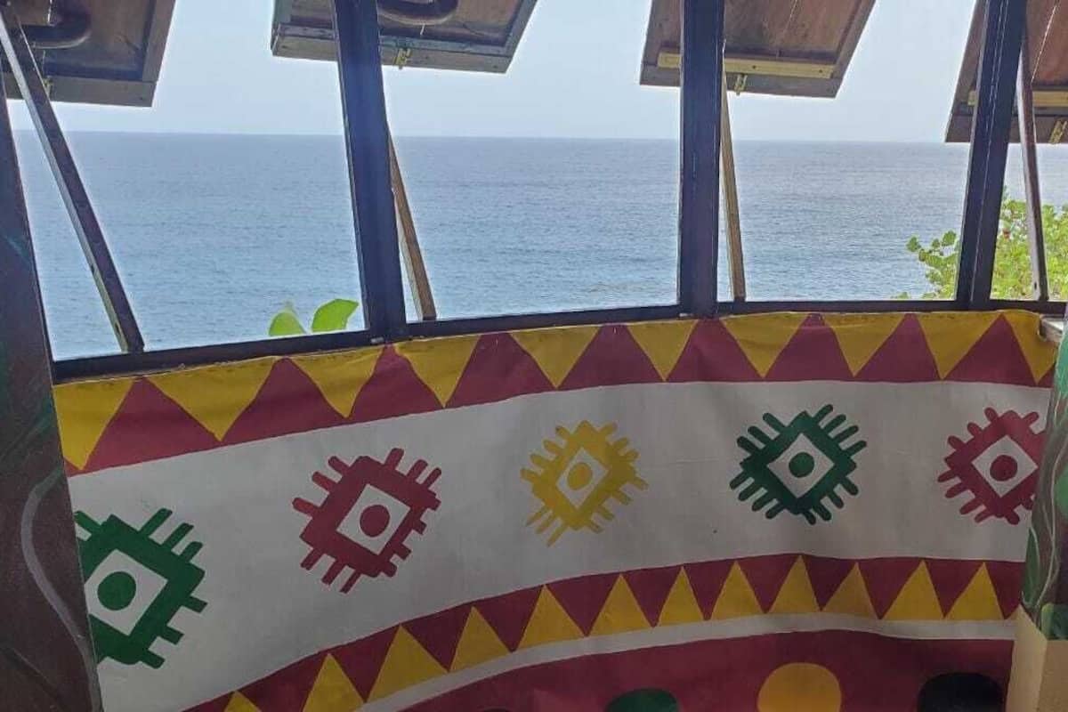 A room with a view of the sea, featuring a colorful patterned wall and a window with a view of the ocean.