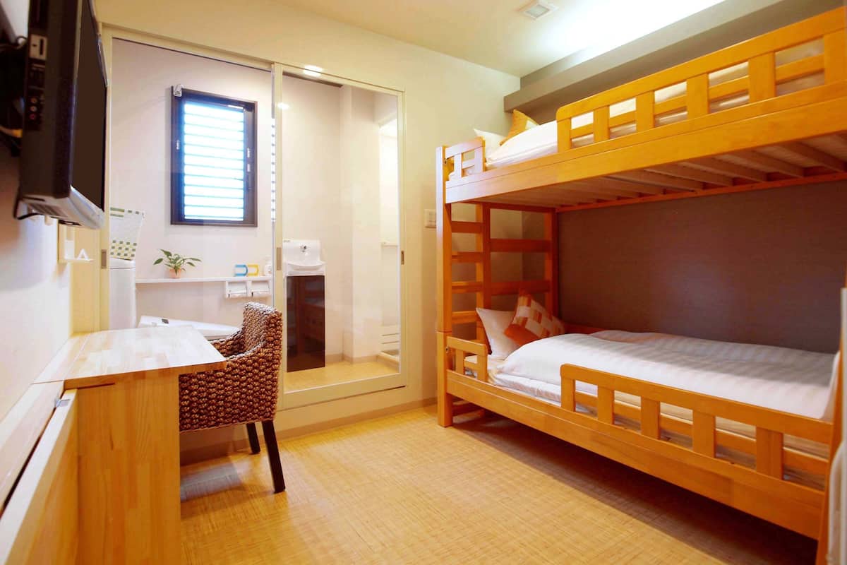 A compact room with a bunk bed, a desk, a chair, and a television.