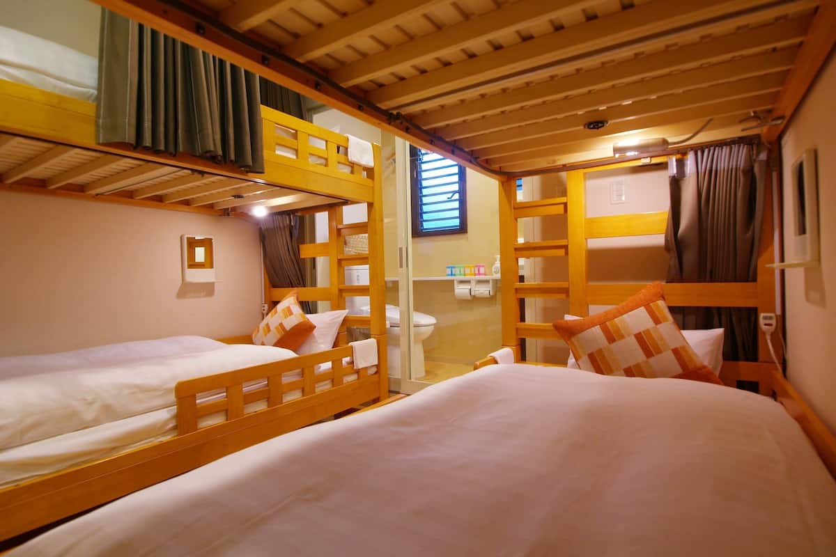 A bunk bed room with a wooden ceiling, a small window, and a mirror.