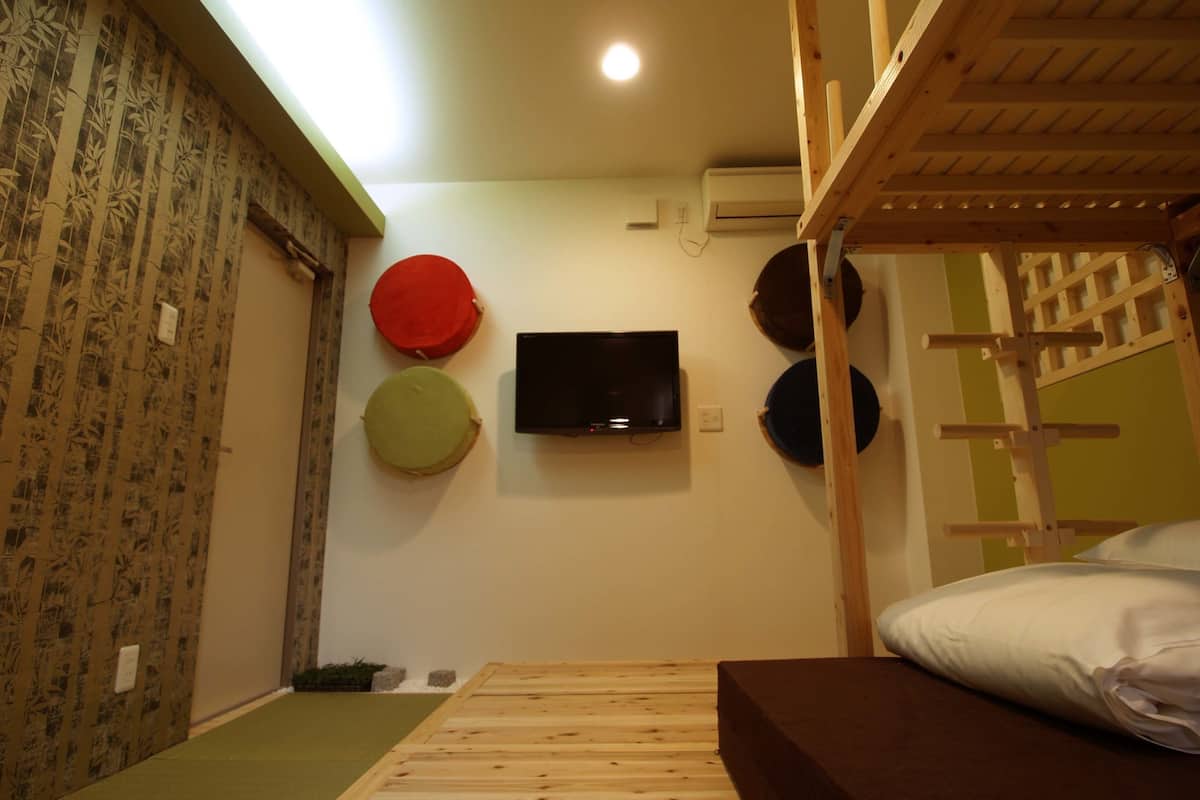 A room with a bunk bed, a flat-screen TV mounted on the wall, and three circular wall decorations.