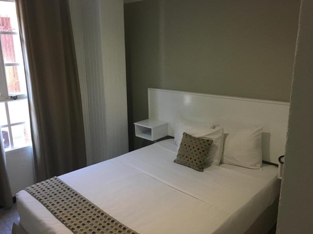 Une chambre d’hôtel avec un grand lit, une table de chevet et une fenêtre avec des rideaux.