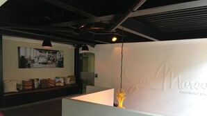 Un espace d’accueil avec un comptoir blanc, une photographie encadrée accrochée au mur et un luminaire décoratif.