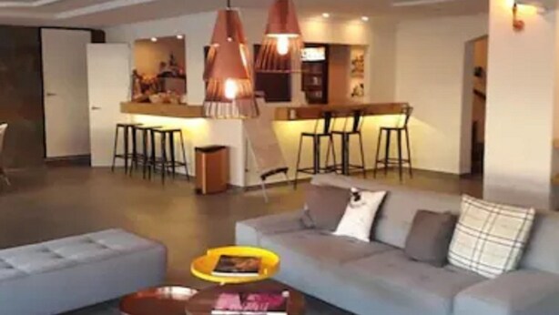 Un salon moderne avec un canapé, une table basse et des luminaires suspendus.