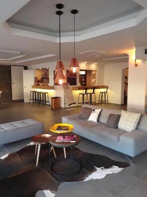 Un salon moderne avec un canapé, une table basse et des luminaires suspendus.