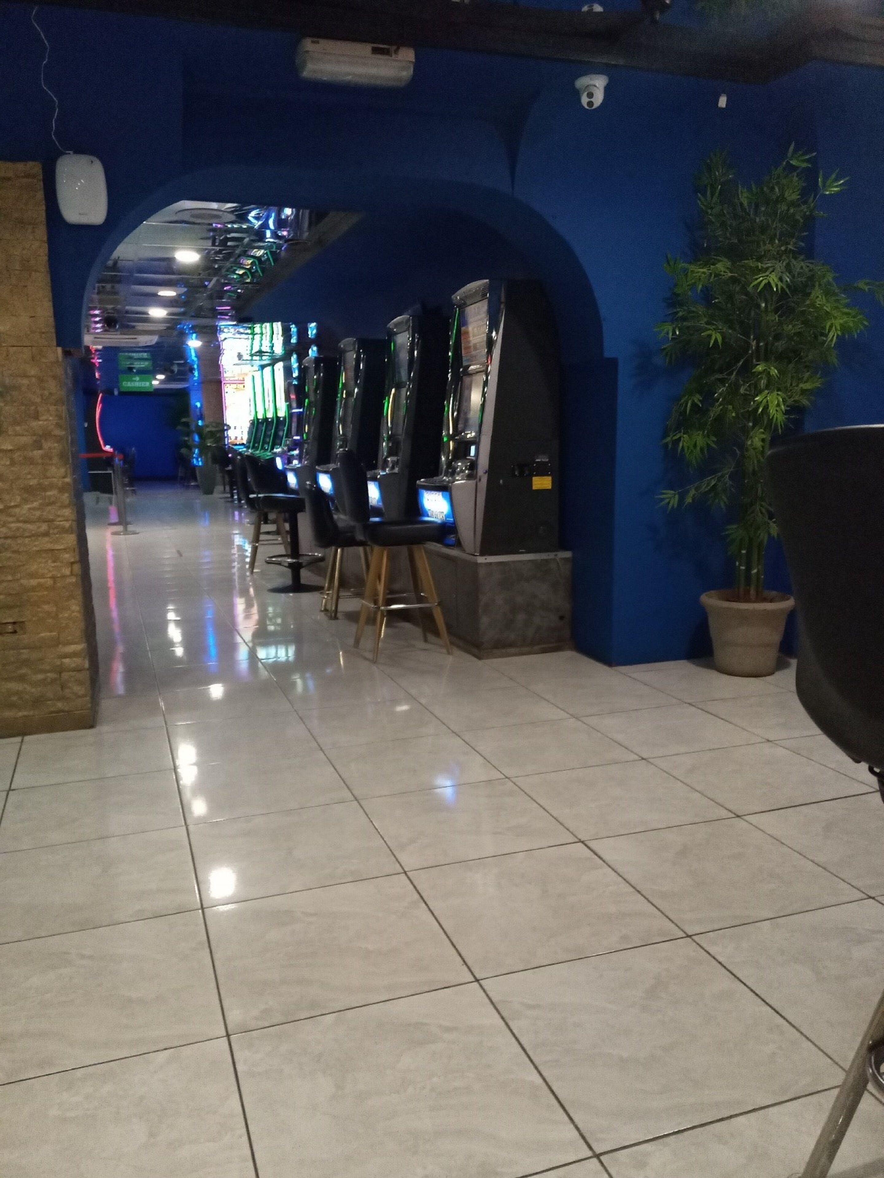 Un corridoio con cabinati arcade, una pianta in vaso e un pavimento piastrellato.