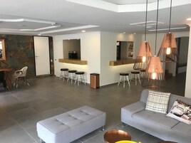 Una sala de estar moderna con un sofá, un reposapiés y una zona de bar con taburetes.