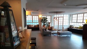 Un vaste espace de vie doté d’un bar en bois, de différents coins salon et de grandes fenêtres laissant entrer la lumière naturelle.