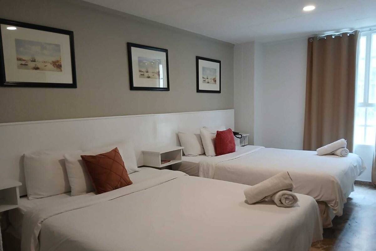 Ein Hotelzimmer mit zwei Betten, einem Nachttisch und gerahmten Bildern an der Wand.