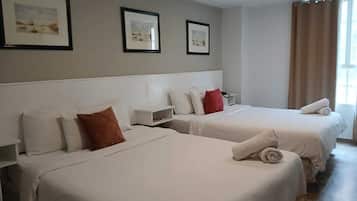 A hotel room with two beds, a nightstand, and framed pictures on the wall.