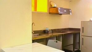 A compact kitchen with a marble countertop, a sink, a refrigerator, and a small cabinet with a decorative item. - The Orchard Cebu Hotel & Suites powered by Cocotel (Mandaue)
