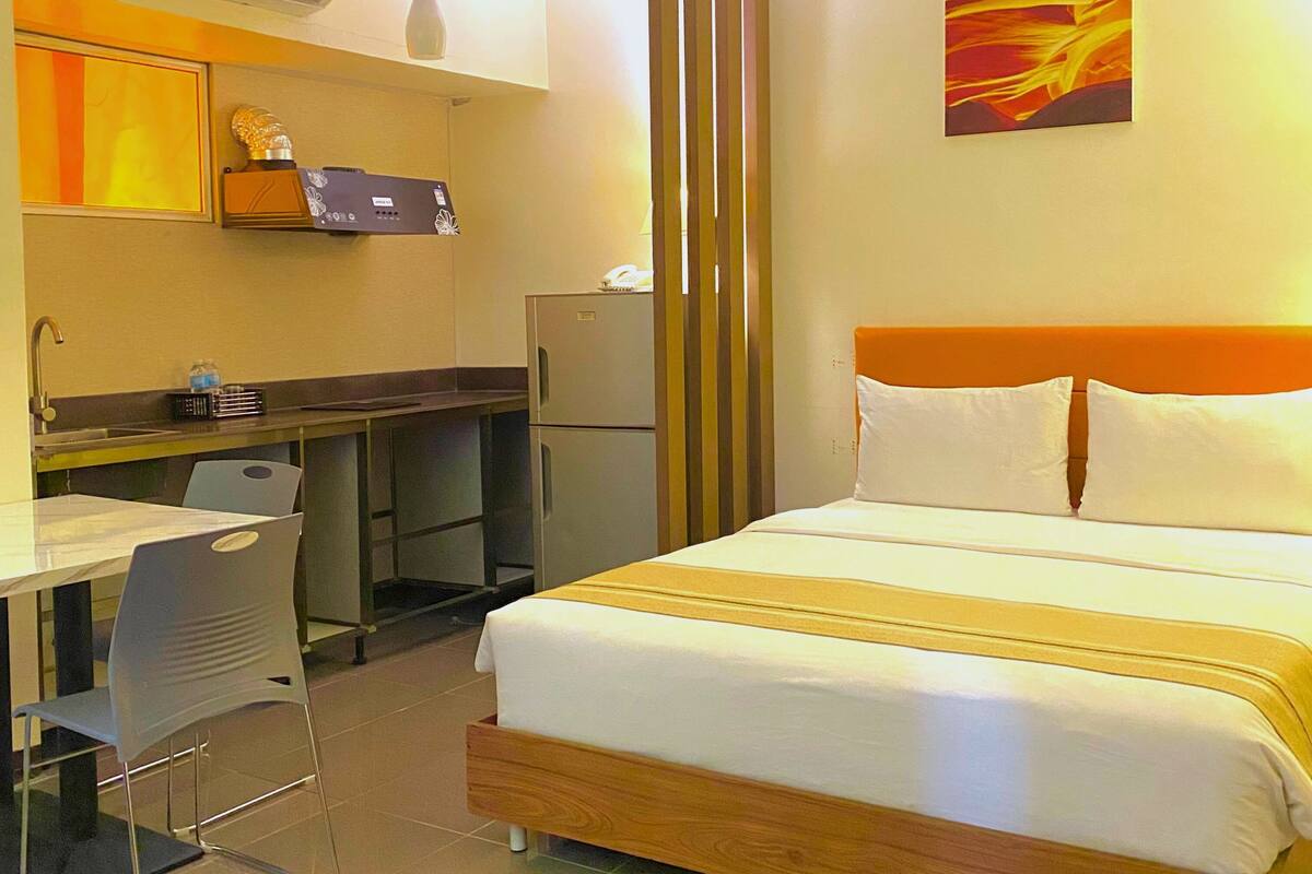 A hotel room with a bed, a desk, and a refrigerator.