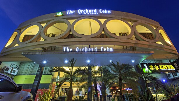 The Orchard Cebu Hotel & Suites with a modern circular facade and illuminated signage. - The Orchard Cebu Hotel & Suites powered by Cocotel (Mandaue)