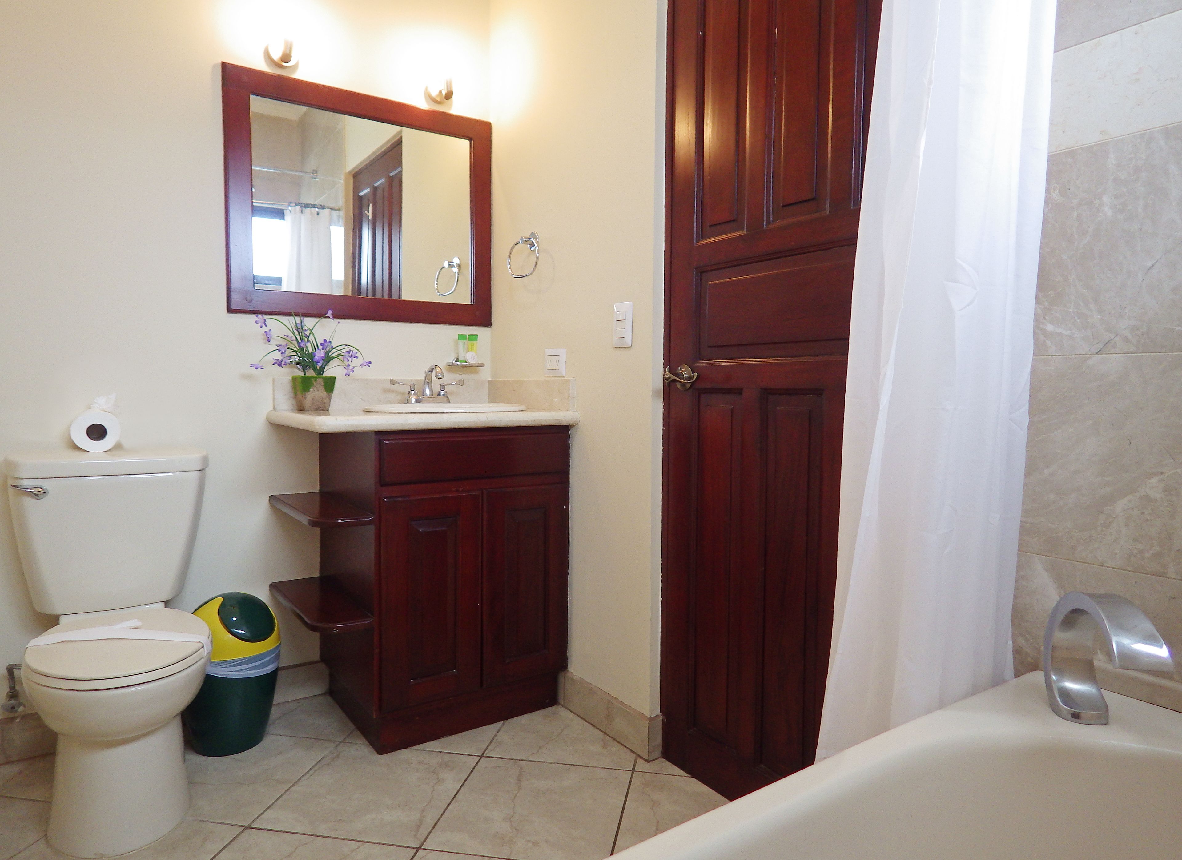 Une salle de bain comprenant des toilettes, un lavabo, un miroir et une baignoire.