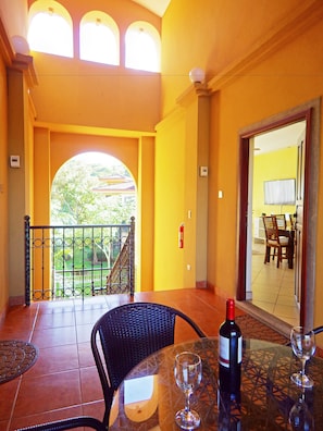 A balcony with a table, chairs, and a bottle of wine.