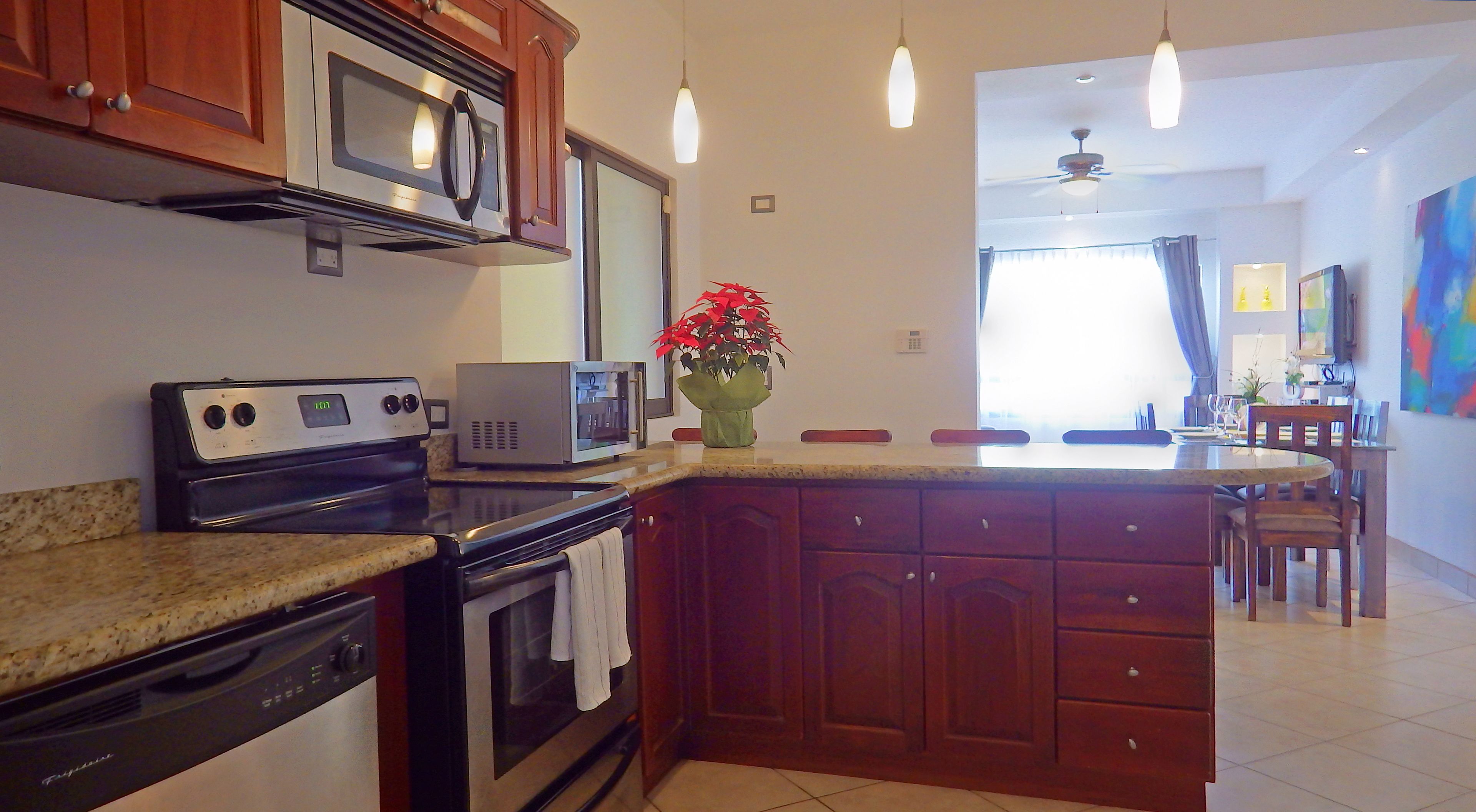 A kitchen with a microwave, stove, and a dining area with a table and chairs.