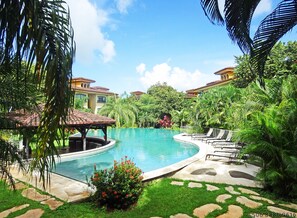 A swimming pool surrounded by lush greenery and a gazebo. - The Oaks Tamarindo Condominiums (Tamarindo)