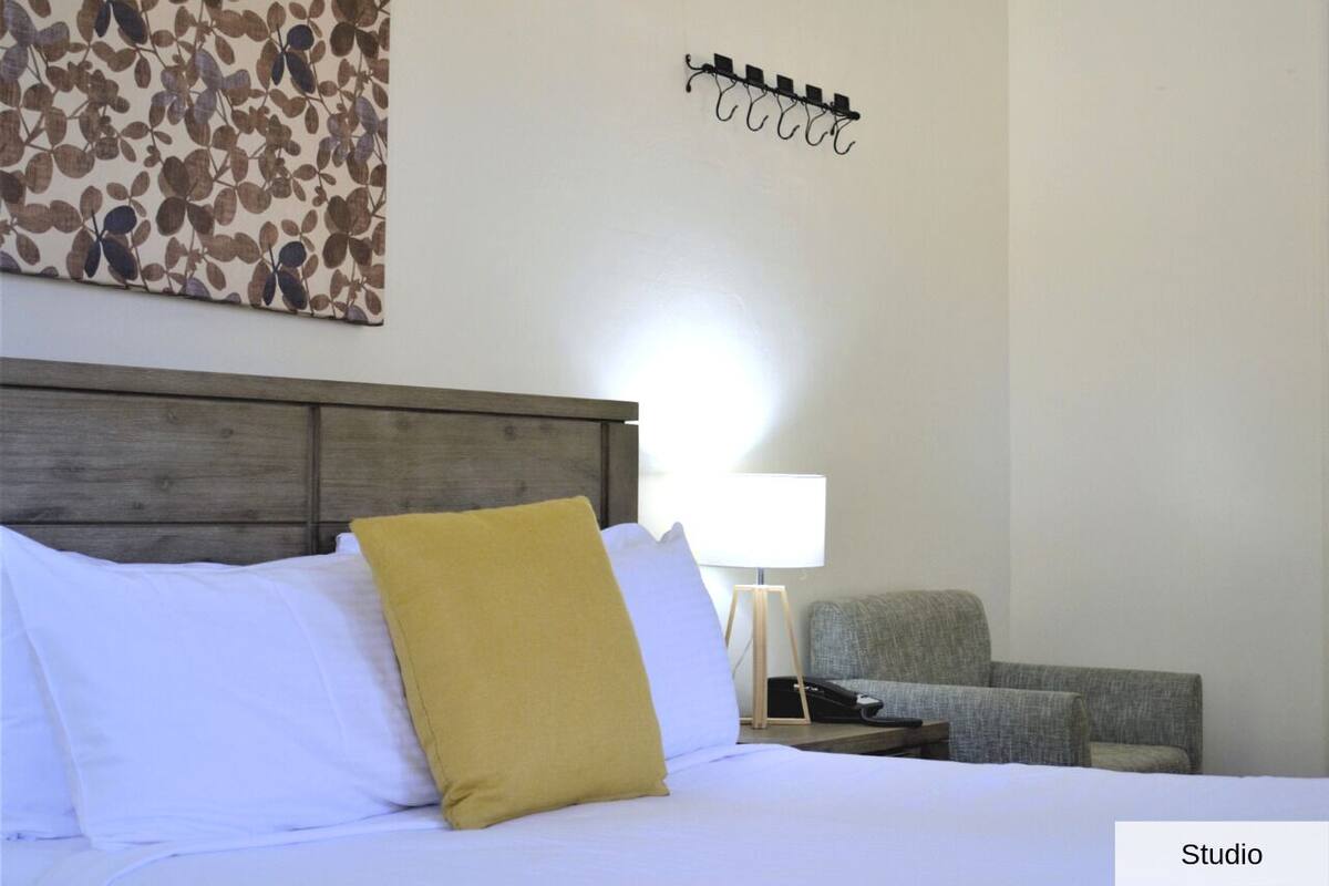 Une chambre d’hôtel avec un lit, une table de chevet, une lampe et une chaise.