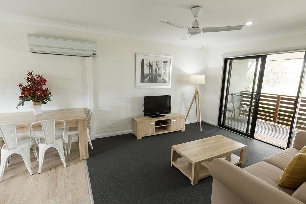 A modern living room with a sofa, coffee table, TV, and dining area.