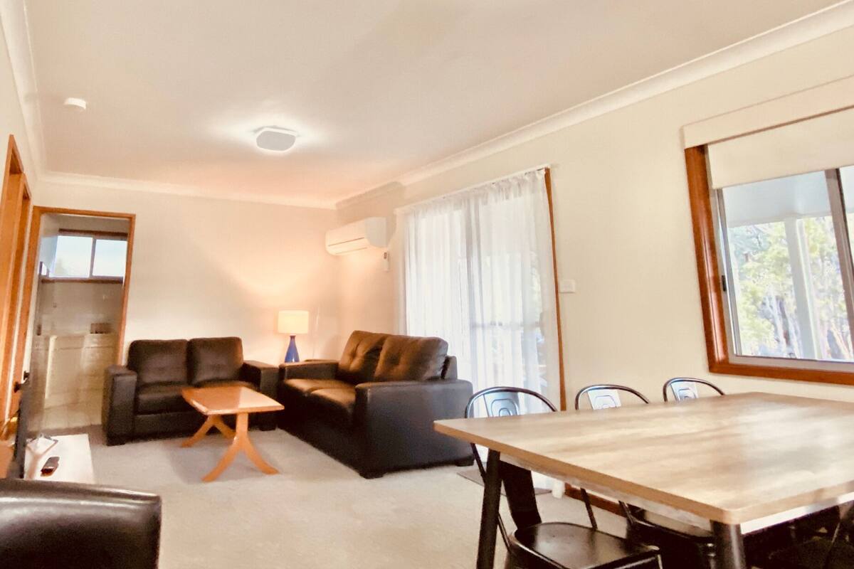 Un salon comprenant un canapé, une petite table basse et une table à manger avec des chaises.