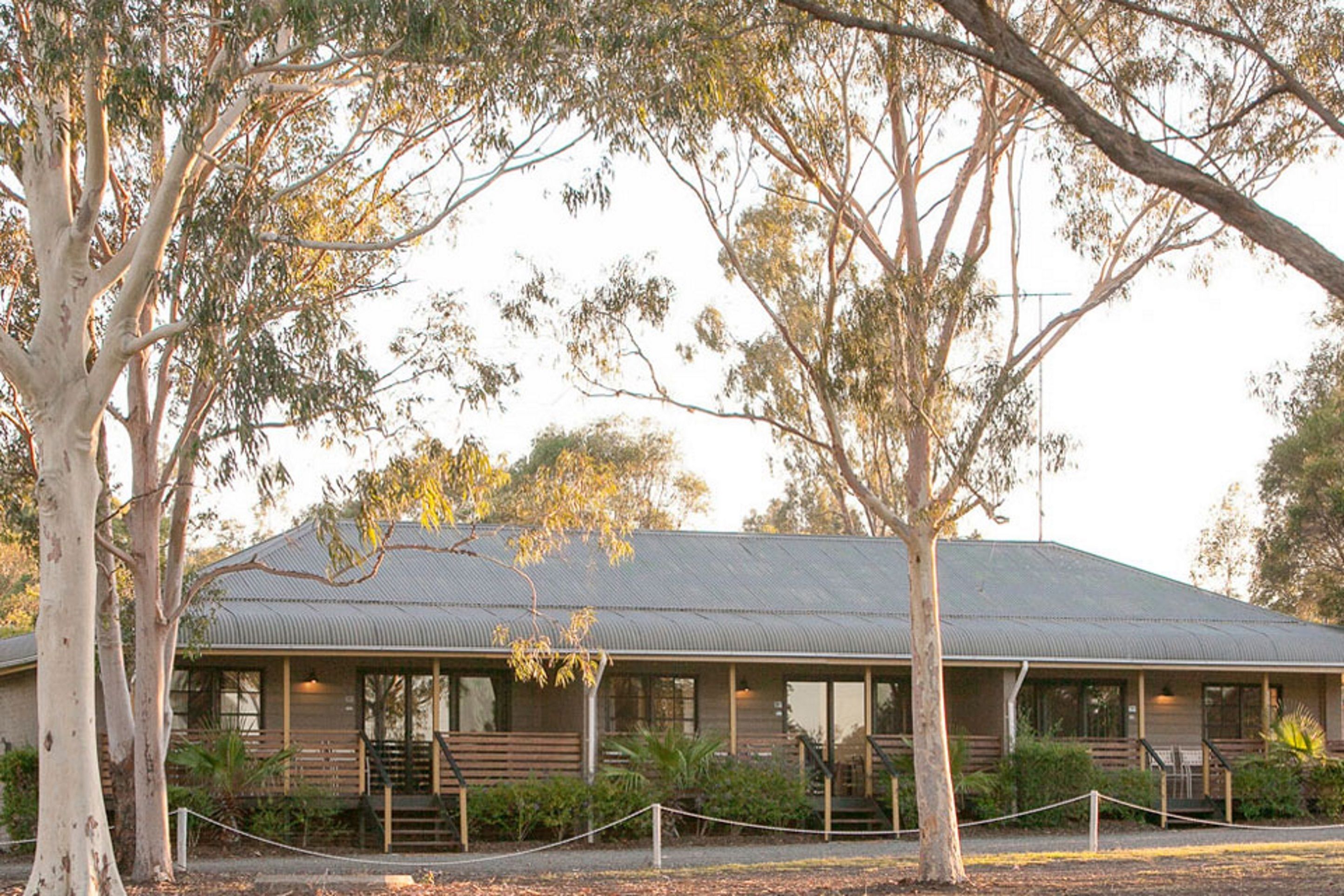 A building with a corrugated metal roof, wooden exterior, and a porch with steps leading to the entrance.