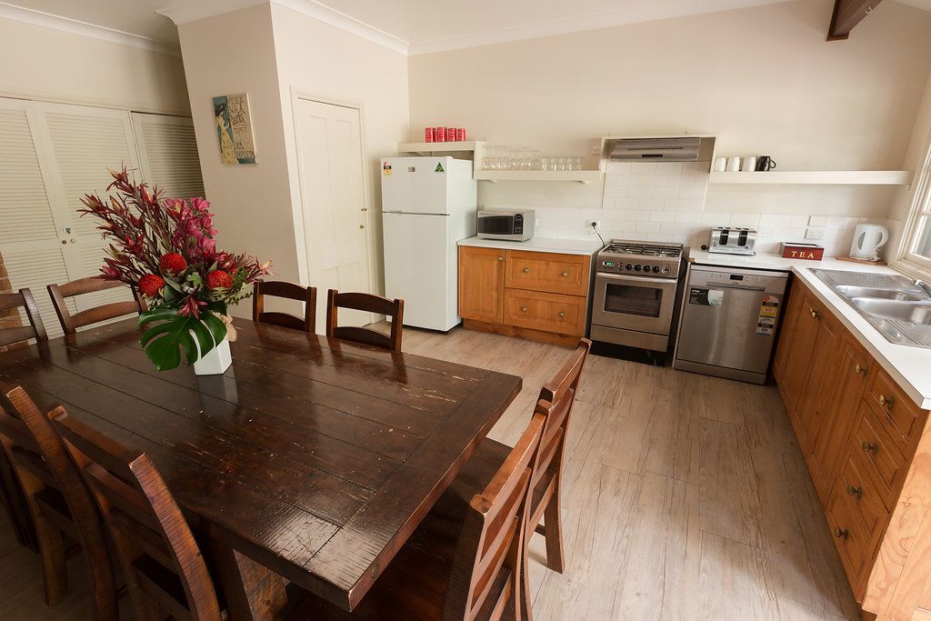 A kitchen with wooden cabinets, a stainless steel refrigerator, a microwave, a stove, and a sink.