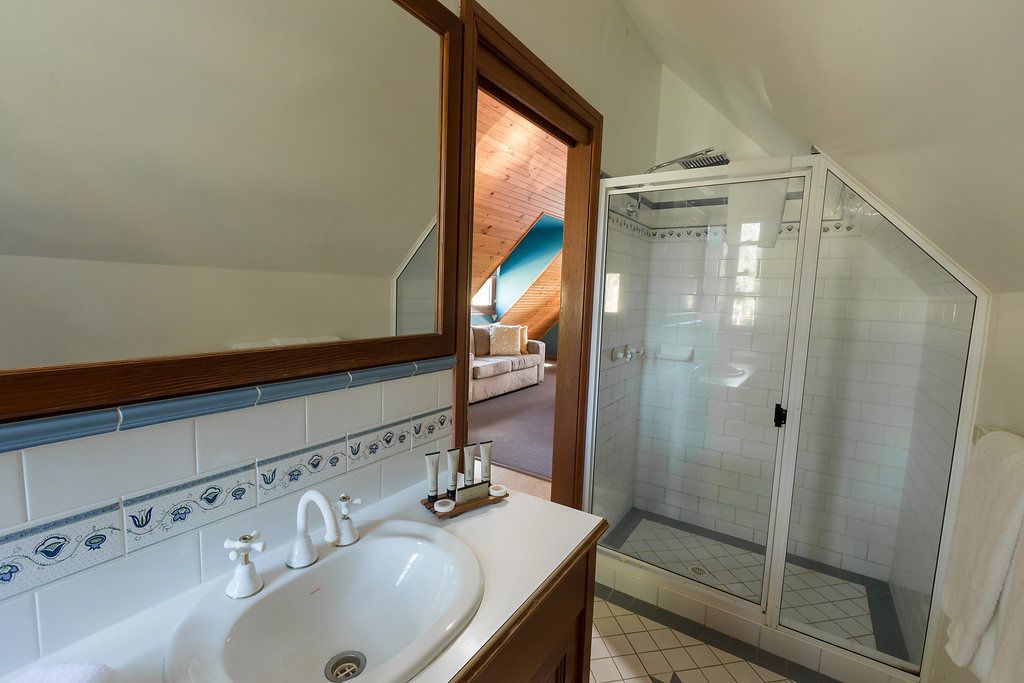 A bathroom with a white sink, a mirror, and a shower enclosure.