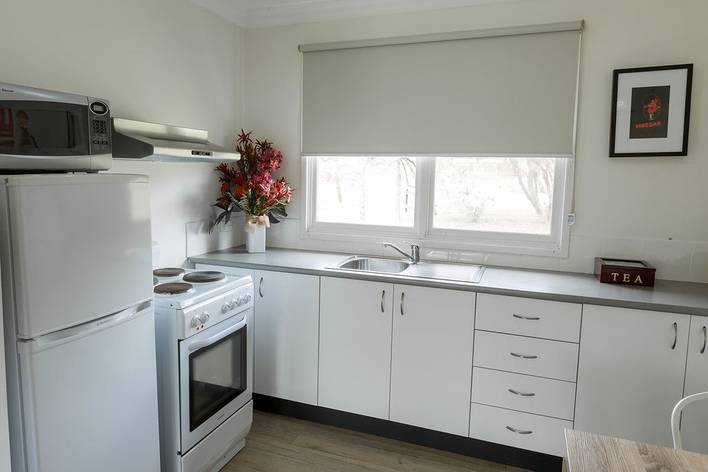 Una cocina moderna con armarios blancos, un microondas, un horno y un fregadero.