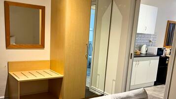 A Deluxe King Suite with a bed, a wooden bench, a wardrobe, and a mirror.