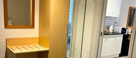 A Deluxe King Suite with a bed, a wooden bench, a wardrobe, and a mirror.