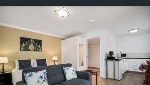 Um apartamento moderno com sofá cinzento, uma pintura, cozinha e área de refeições.