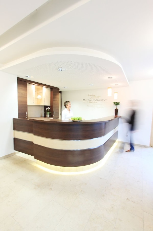 A reception desk with a modern design, a welcome sign, and a potted plant.