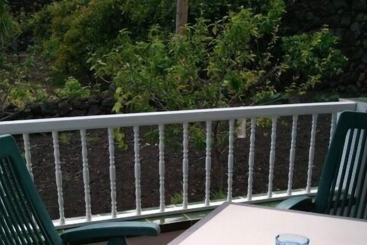 A patio area with a white table and two green chairs.