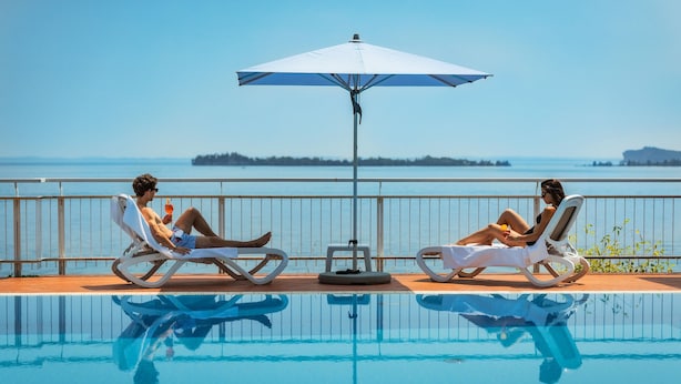 Dos sillones de descanso junto a una piscina con vista al mar.