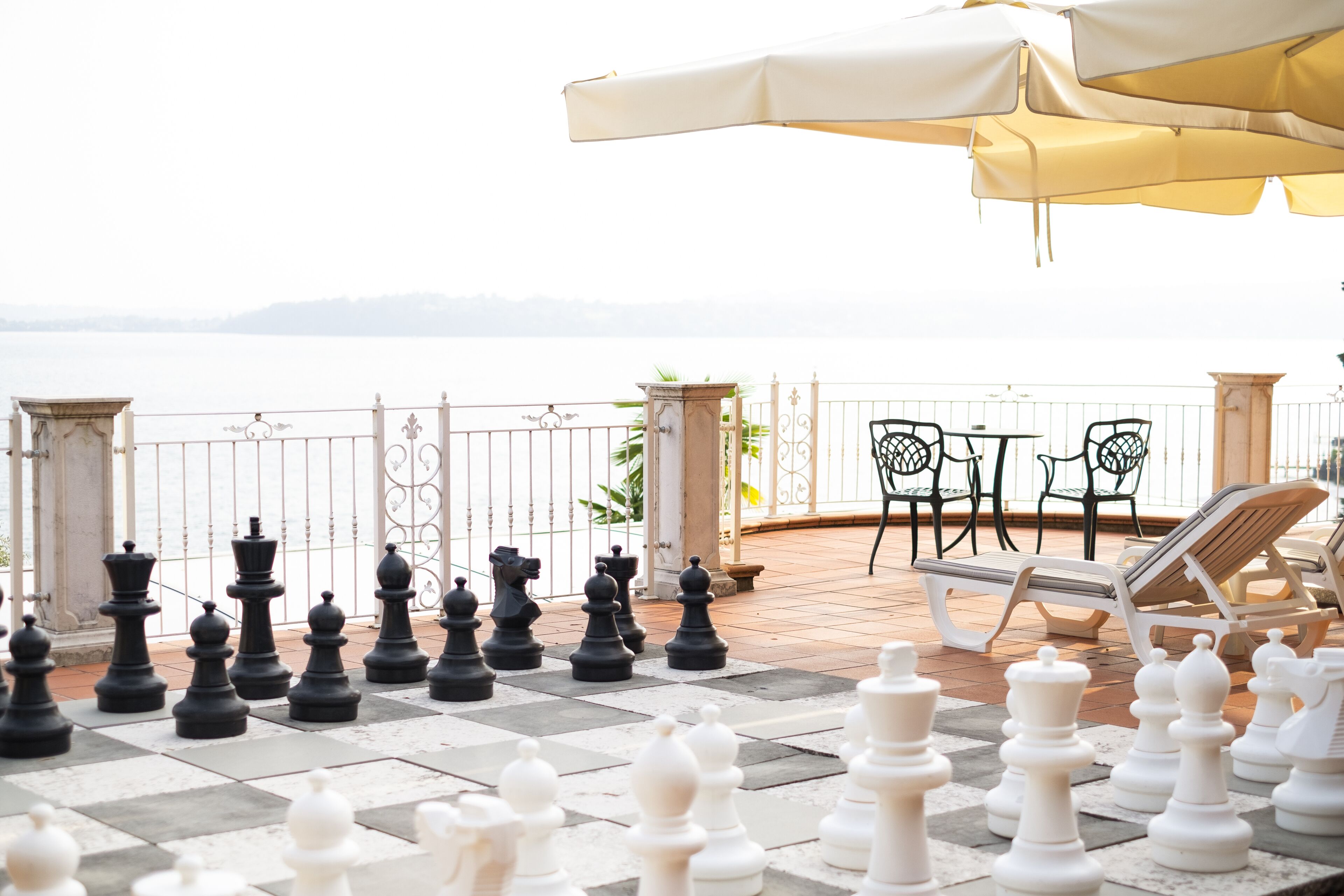 A chessboard set up on a terrace with a view of the sea.