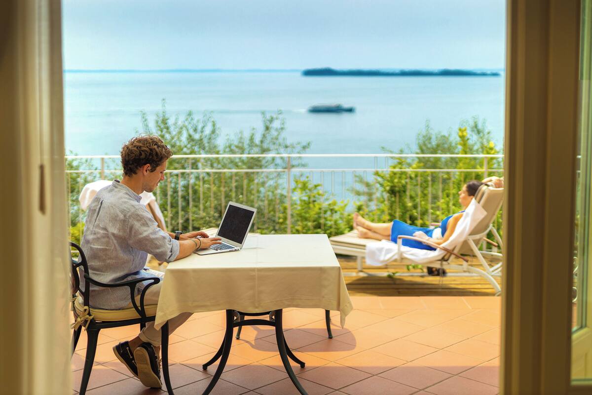 A balcony with a table and chairs, overlooking a body of water.