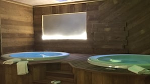A spa area with two hot tubs, wooden steps leading to them, and a tiled floor. - Relais des Alpes (Sauze d'Oulx)