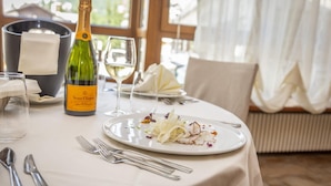 A dining table set with a bottle of Veuve Clicquot champagne, a glass of white wine, and a plate of food. - Relais des Alpes (Sauze d'Oulx)