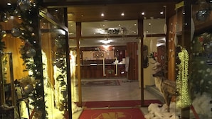 A hotel entrance with a red carpet leading to a reception area, decorated with Christmas ornaments and a reindeer statue. - Relais des Alpes (Sauze d'Oulx)