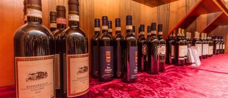 A row of wine bottles on a red tablecloth in a wooden room.