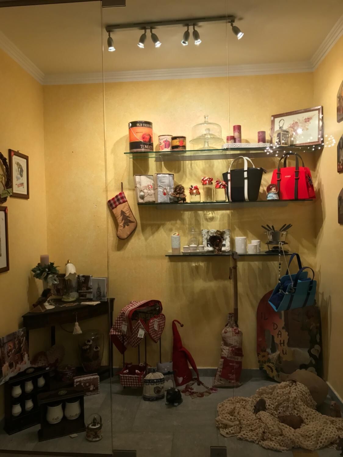 A cozy room with shelves displaying various items, a small table with a lamp, and a teddy bear on the floor.
