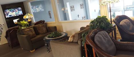 A cozy living room with a sofa, armchairs, a coffee table, and a TV.