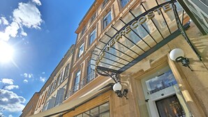 La façade d’un hôtel, avec une enseigne indiquant « HÔTEL NEGRESCI », de grandes fenêtres et un balcon orné d’une balustrade en fer forgé.