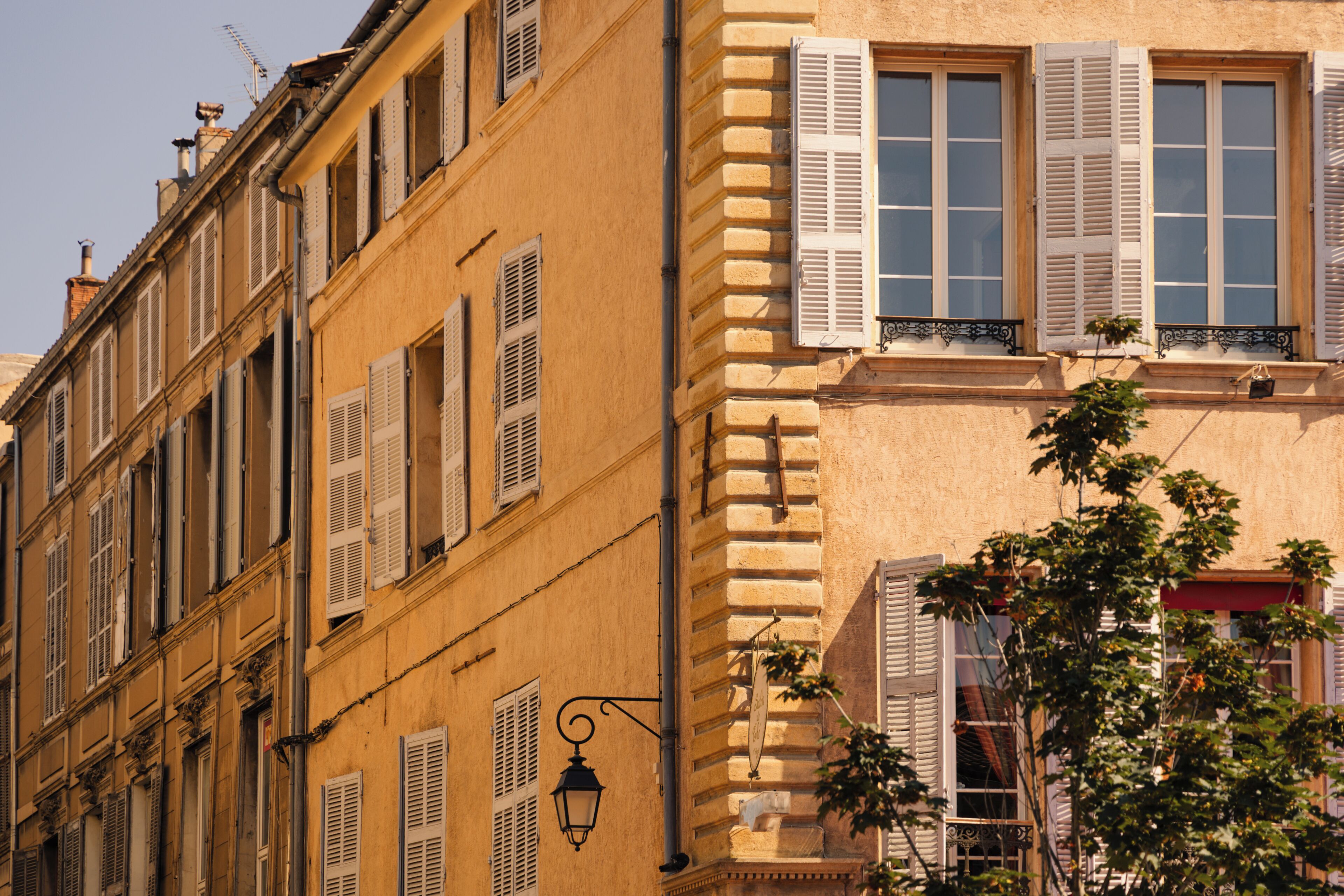 A building with multiple windows, shutters, and a street lamp.
