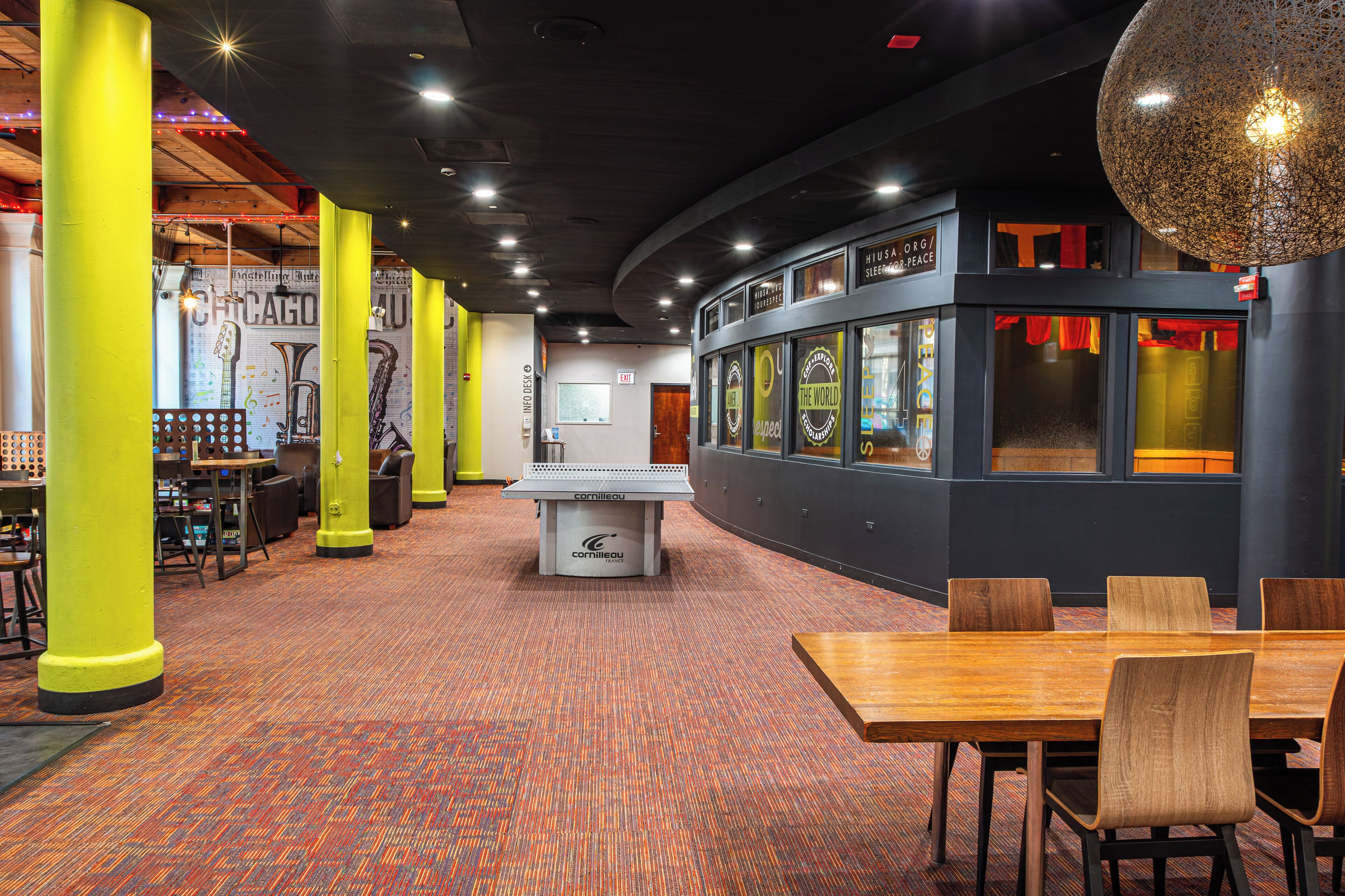 A modern interior with a central information desk, seating areas, and a wall with informational posters.