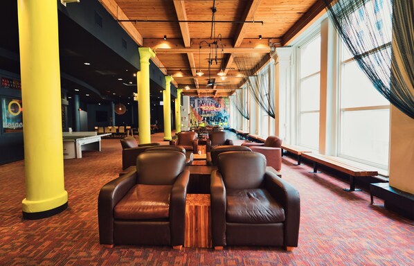 A spacious hotel lobby with leather seating, wooden tables, and large windows.