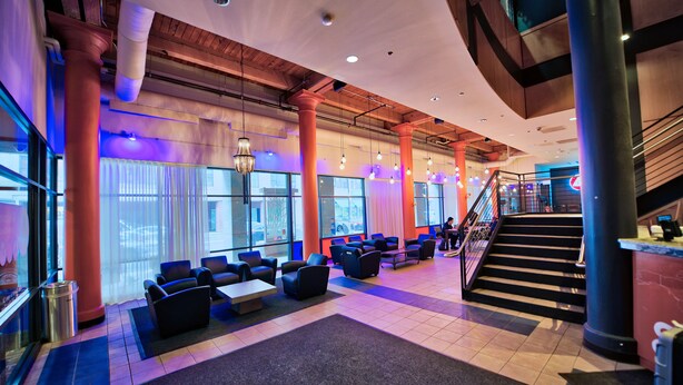 A spacious lobby with seating areas, a staircase, and large windows. - HI Chicago Hostel (Chicago)