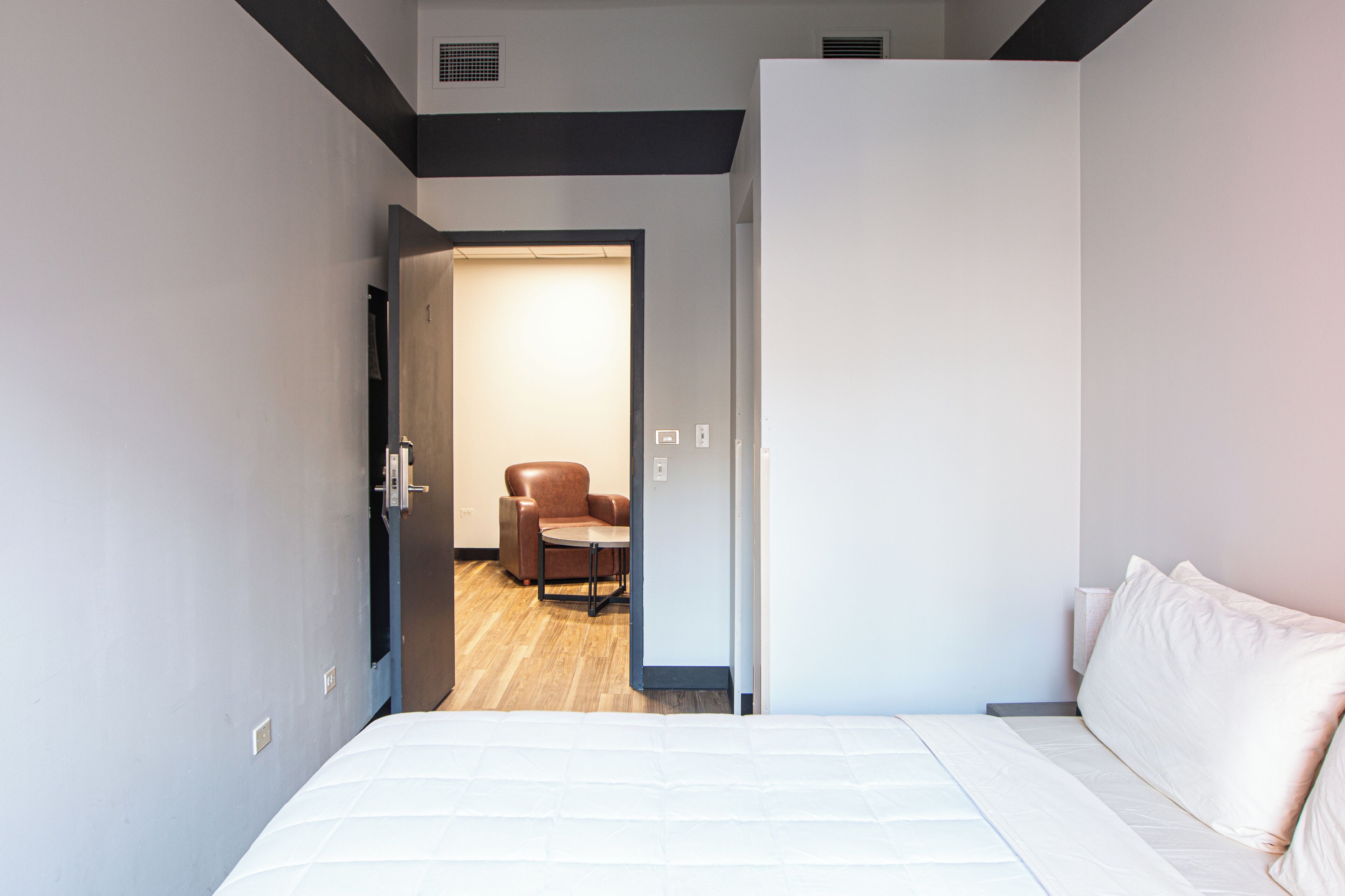 A hotel room with a bed, a chair, and a small table.