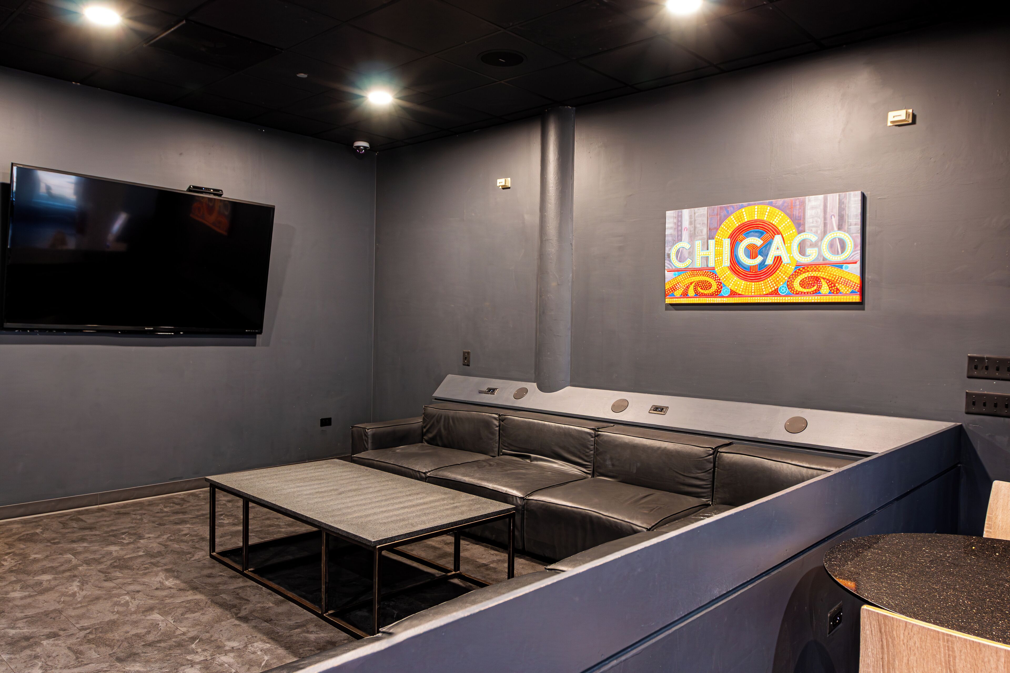 A modern home theater room with a large flat-screen TV, a sectional sofa, and a "CHICAGO" mural on the wall.
