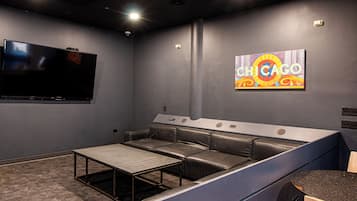 A modern home theater room with a large flat-screen TV, a sectional sofa, and a "CHICAGO" mural on the wall.
