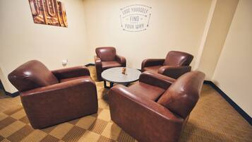 A conference room with four brown leather chairs around a small round table, a motivational quote on the wall, and a patterned carpet.